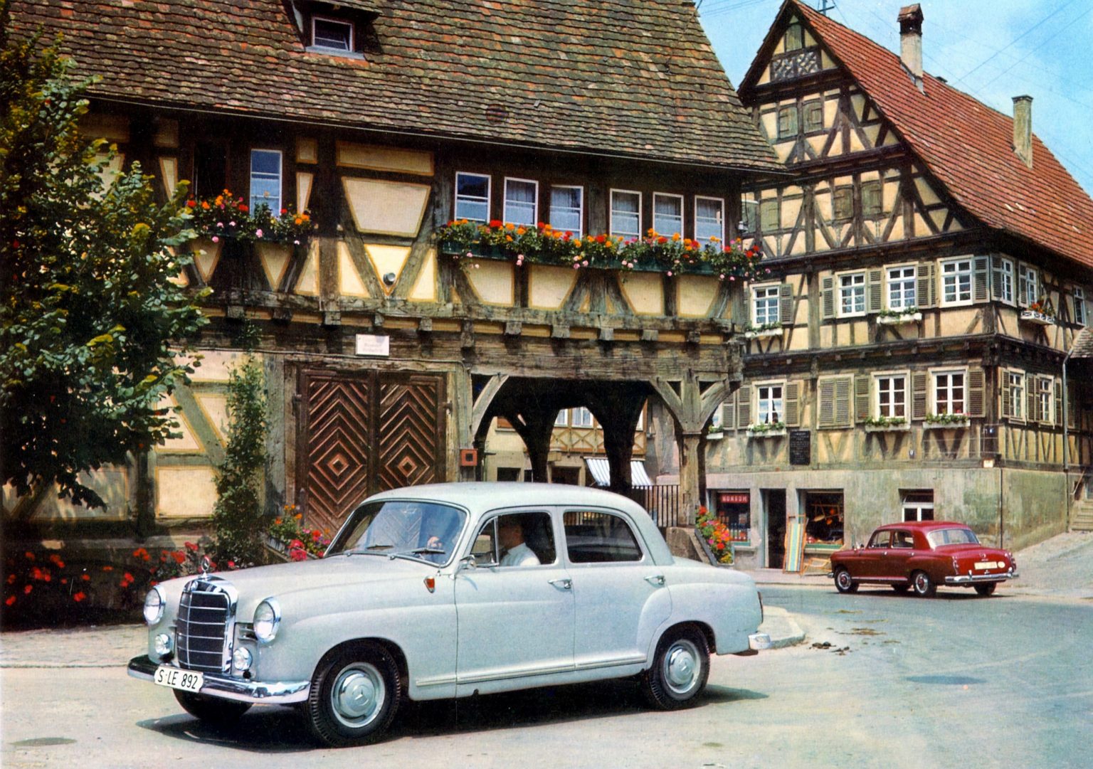 Star of the Heimatfilm (sentimental films in idealised regional settings popular in the 50s): "Ponton Mercedes" saloon (Mercedes-Benz 120/121 series, 1953 to 1962) against a half-timbered house backdrop.